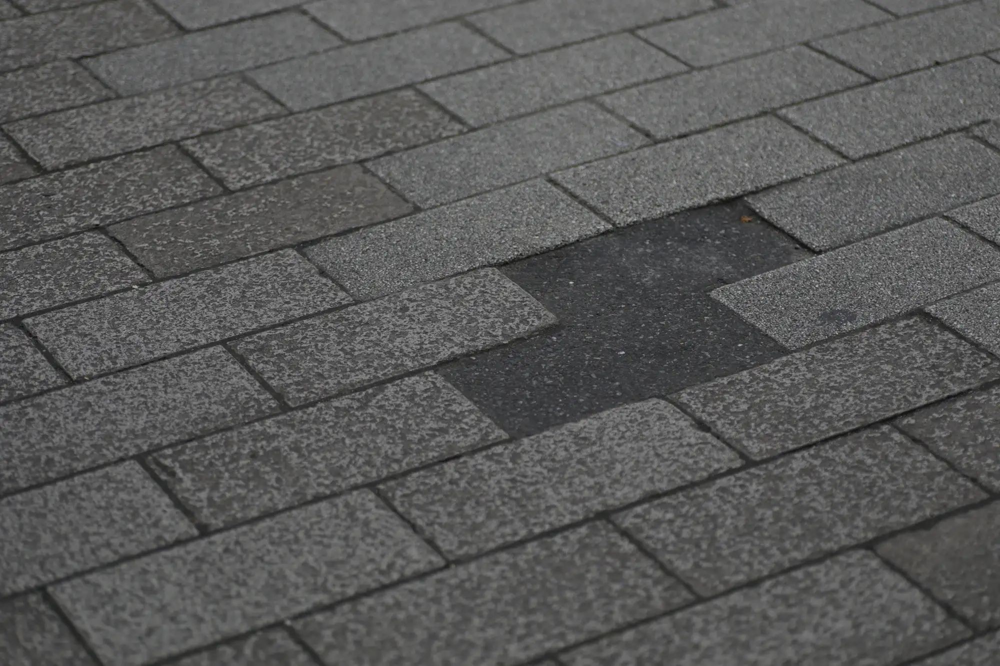 An asphalt shingle roof with missing and damaged shingles